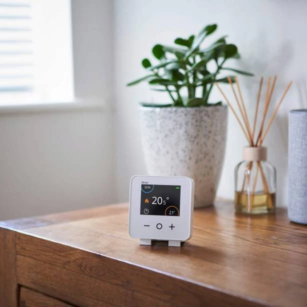 Smart thermostat with colour display on an oak side table in a North London home
